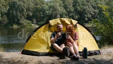<strong>旅游</strong>和<strong>旅游</strong>的概念.. 年轻的幸福夫妇坐在帐篷里<strong>看</strong>风景。 喝茶，笑着说话